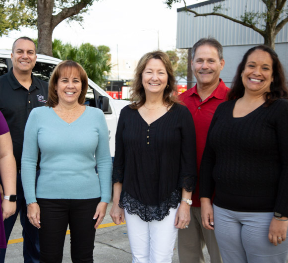 A group of ATI employees in a parking lot smiling.