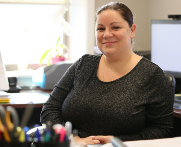 Smiling dark haired ATI employee sitting at her desk